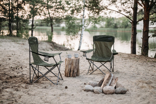 Two empty camping chairs facing a lake