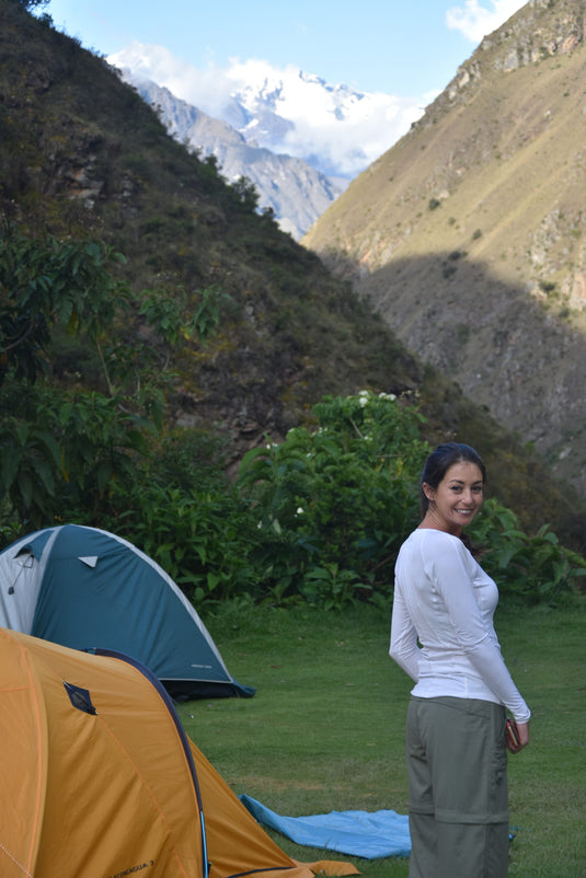 Beautiful woman standing by her campsite with mountains in the background