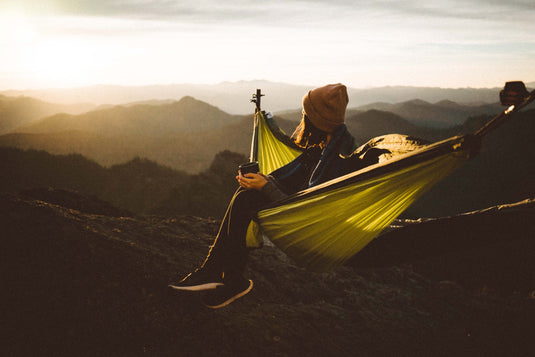 Hiker lays in their hammock looking off into the mountain range horizon